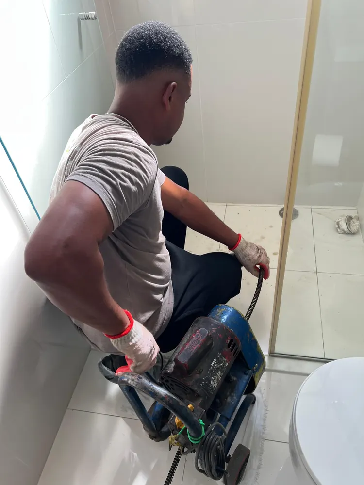 Técnico desentupindo o ralo do banheiro com máquina